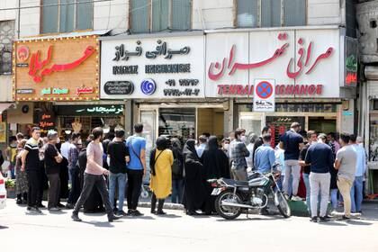Filas desordenadas frente a una oficina de cambio en Teherán el 9 de mayo de 2020 (Foto de ATTA KENARE / AFP)