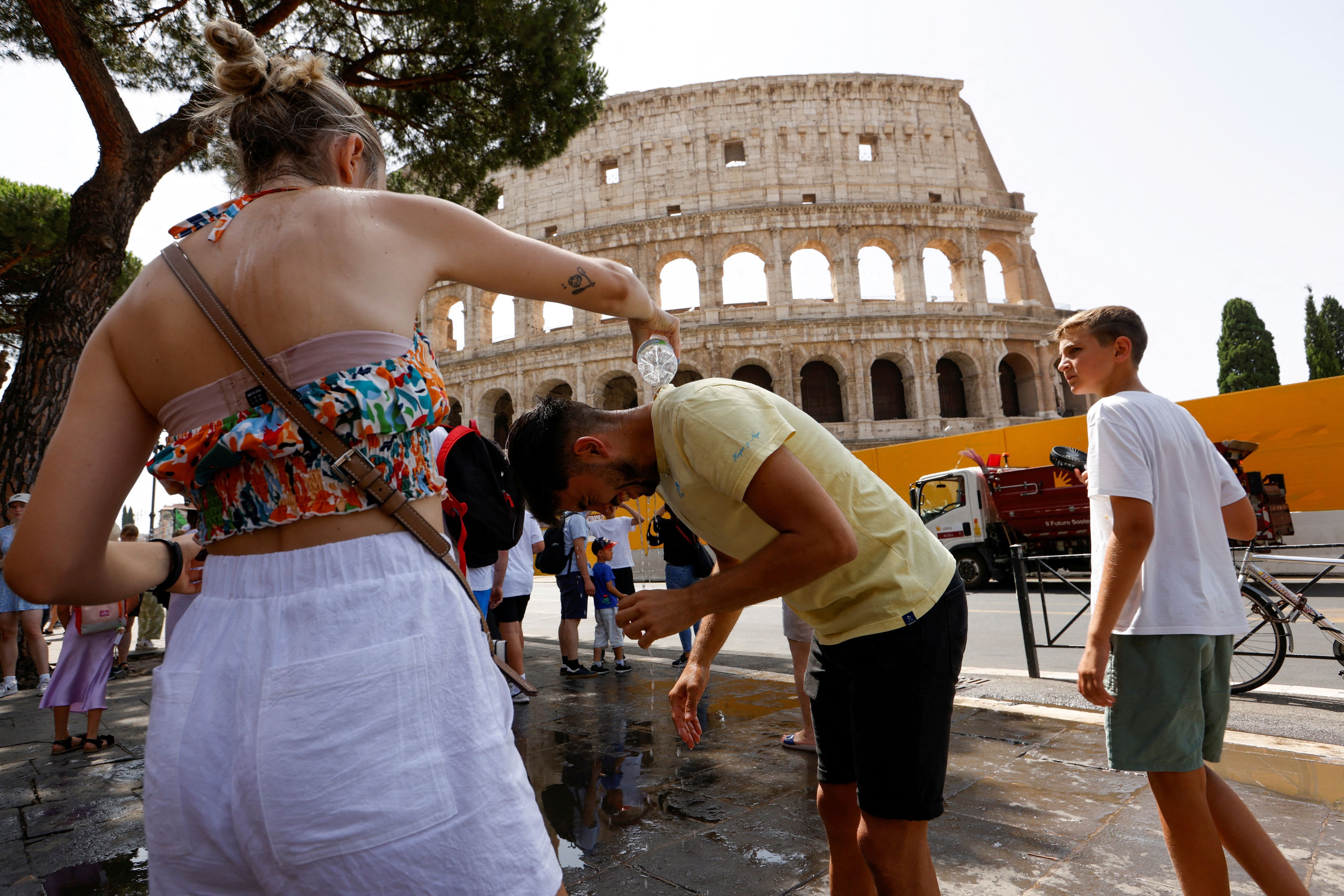 Una mujer vierte agua sobre un hombre cerca del Coliseo durante una ola de calor en toda Italia, en Roma, Italia. 18 de julio de 2023. REUTERS/Remo Casilli/Foto de archivo