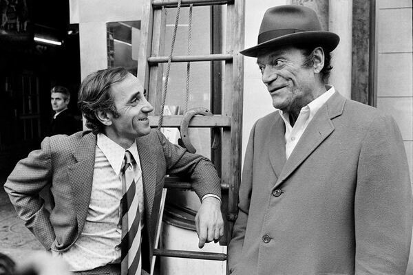 Charles Aznavour y Eddie Constantine conversan en una calle de París en noviembre de 1972 (AFP)