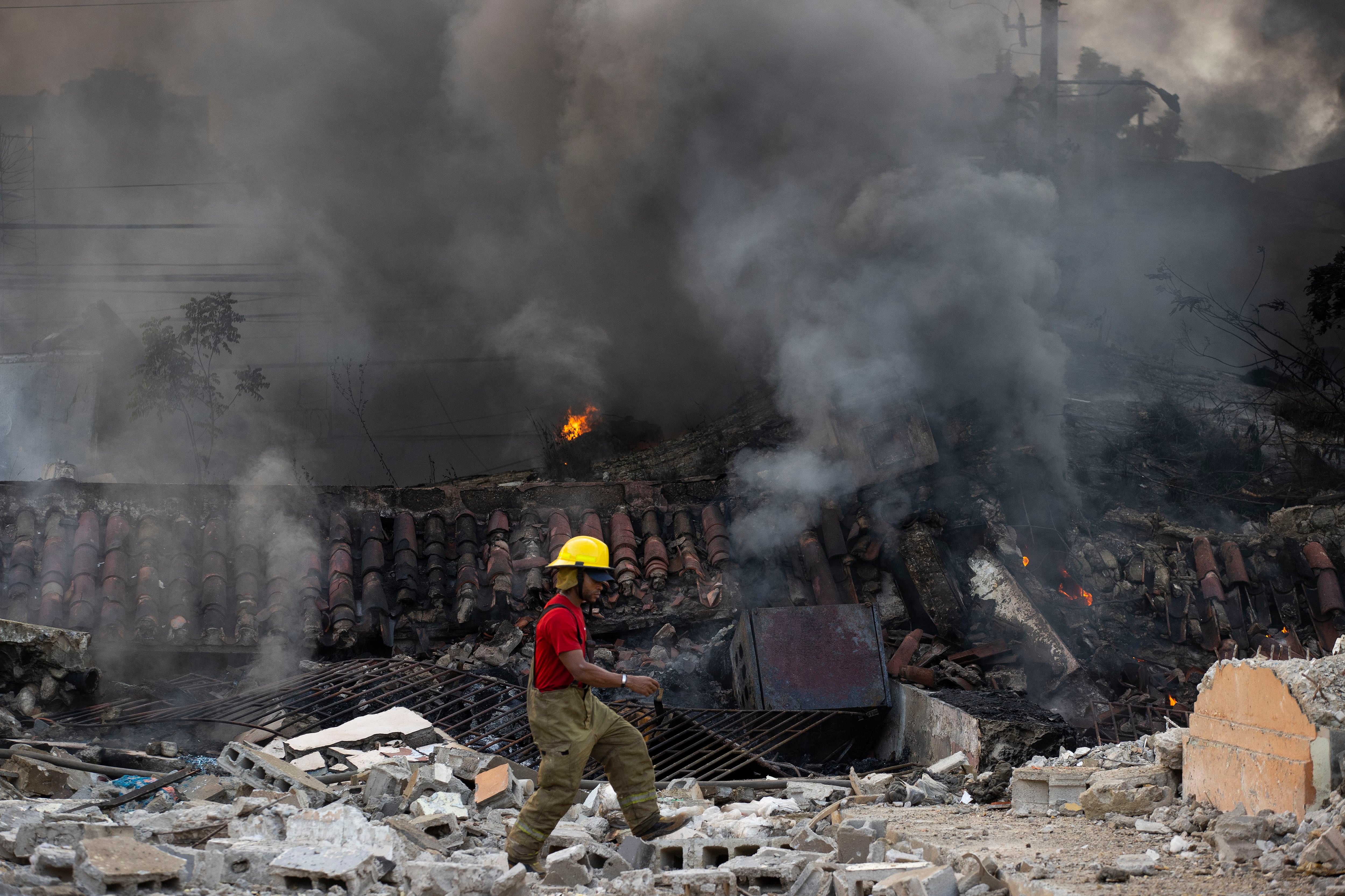 Un integrante de los bomberos pasa frente a locales afectados por una explosión en San Cristóbal (EFE/ Orlando Barría)