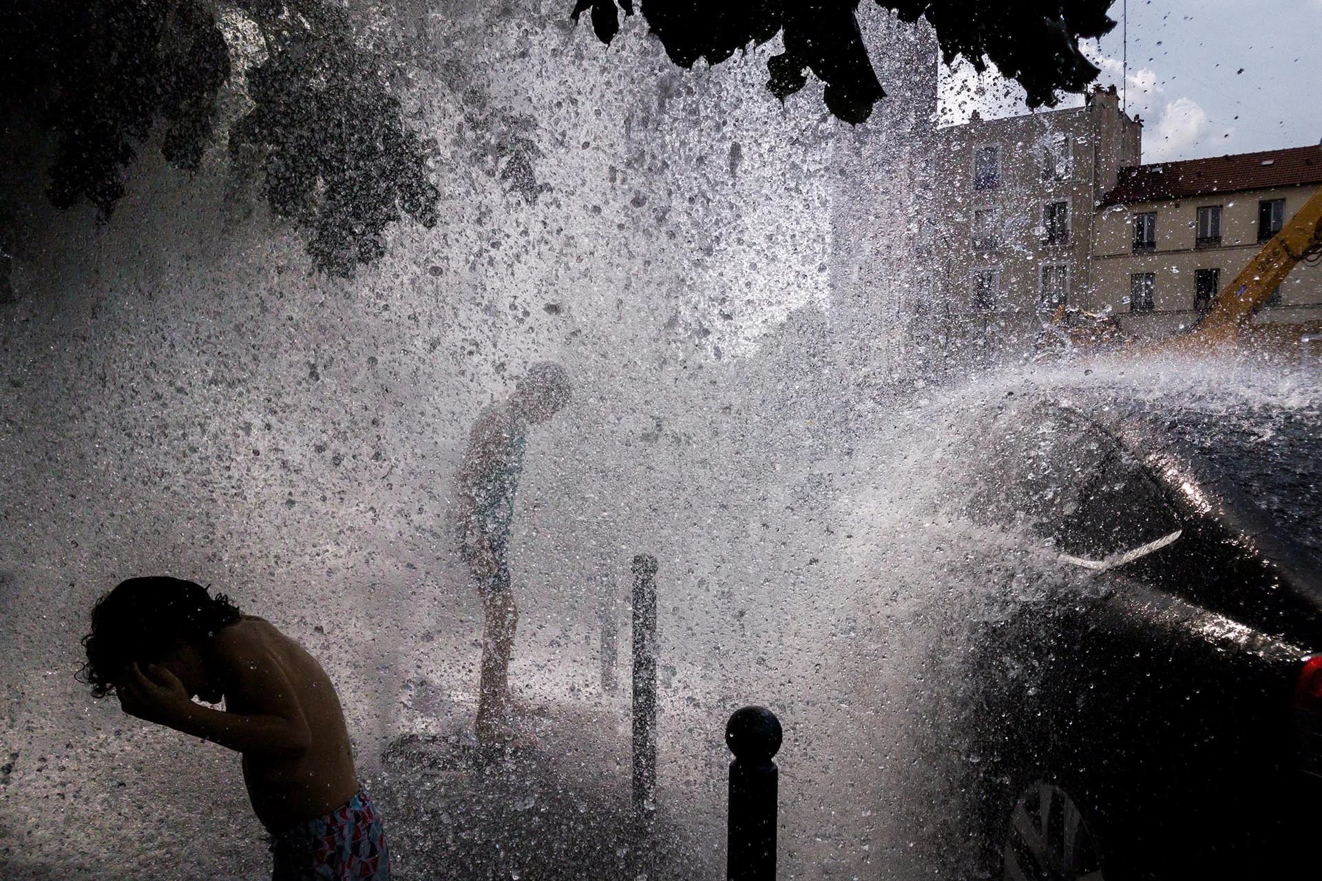 La gente se refresca con el agua de una boca de incendios abierta en Pantin, cerca de Porte de La Villette, al norte de París