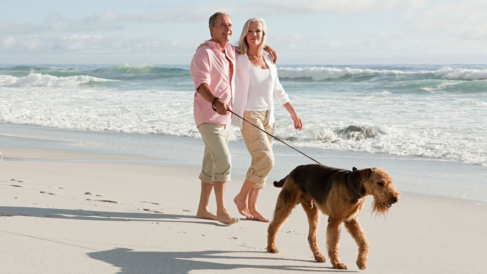 Dos jubilados junto a su perro en una playa (Getty Images).
