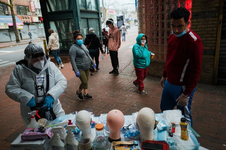 Vivien Grullon, a la izquierda, vende mascarillas, guantes y artículos de limpieza debajo de la estación del tren 7 en la avenida Roosevelt en Jackson Heights, Queens. (Ryan Christopher Jones / The New York Times)