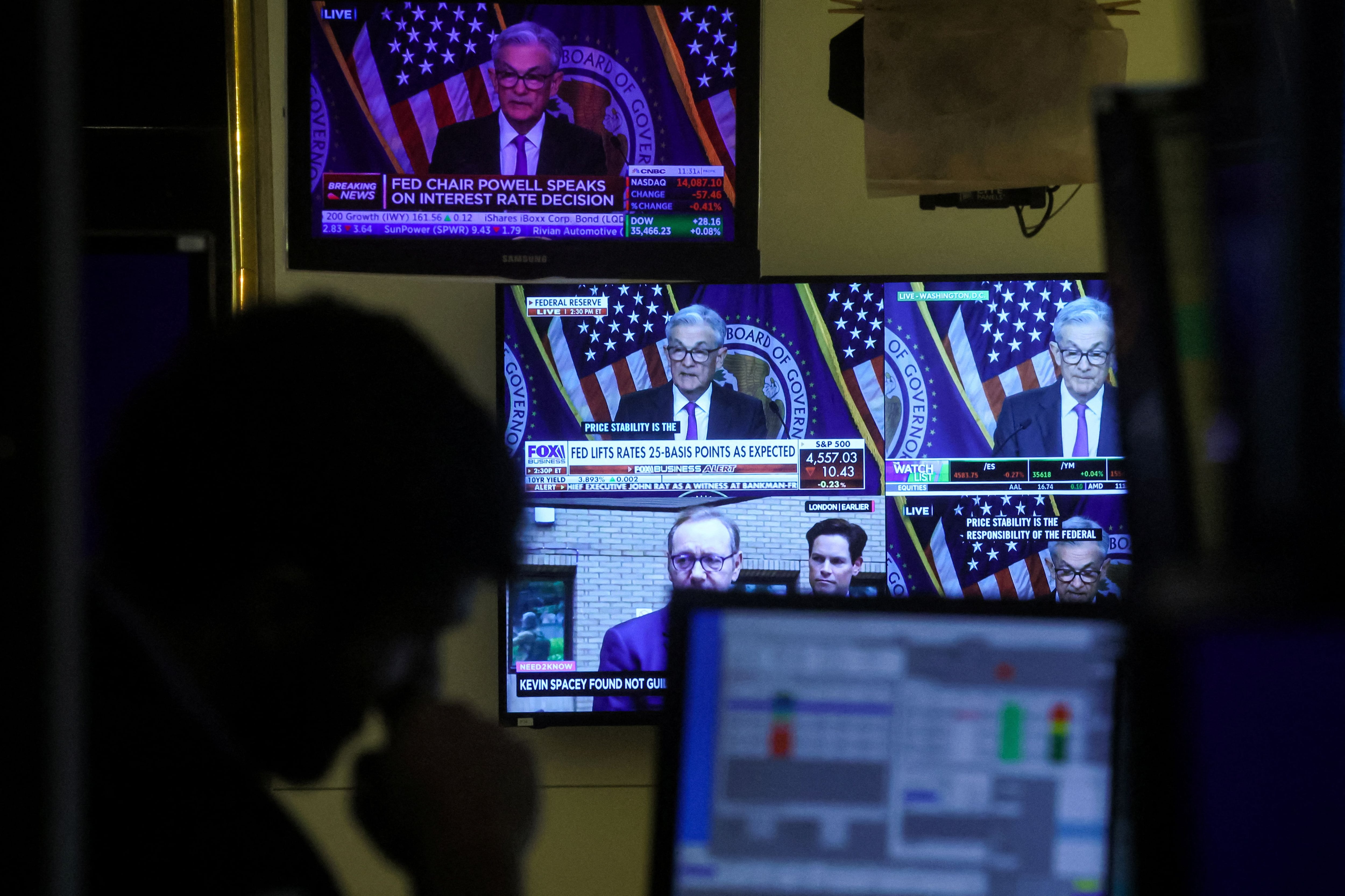 Un operador de bolsa trabaja dentro de una cabina, mientras las pantallas muestran una rueda de prensa del presidente de la Reserva Federal, Jerome Powell, tras el anuncio de tipos de la Fed (REUTERS/Brendan McDermid).