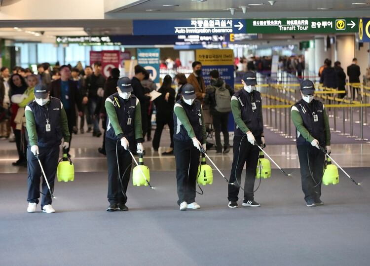 Los trabajadores rocían una solución antiséptica en el vestíbulo de llegadas en medio de las crecientes preocupaciones del público sobre la posible propagación de un nuevo coronavirus en el Aeropuerto Internacional de Incheon en Incheon, Corea del Sur, el martes 21 de enero de 2020. Se tomaron mayores precauciones en China y en otros lugares el martes como gobiernos se esforzó por controlar el brote de un nuevo coronavirus que amenaza con crecer durante el viaje del Año Nuevo Lunar. (Suh Myung-geon / Yonhap vía AP)