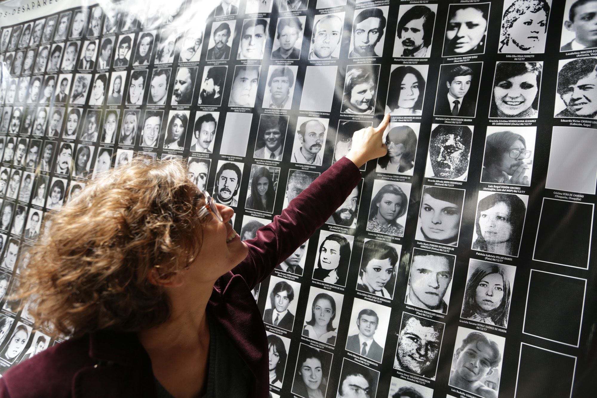 Giglio señala con una sonrisa el retrato de su madre dentro de un cartel en el lugar donde estaba ubicado el centro de tortura El Atlético. (Gentileza Valeria Perasso, BBC Mundo)