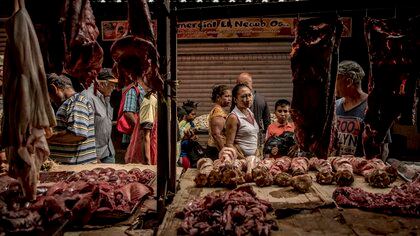 Personas que compraban despojos no refrigerados y otros subproductos de carne de res en un mercado de Maracaibo.  (Meridith Kohut/The New York Times)