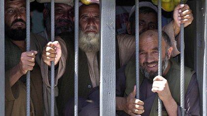 Prisioneros afganos entregados a las autoridades afganas después de su liberación del centro de detención de máxima seguridad en la bahía de Guatanamo esperan en la prisión de Kabul, el 10 de mayo de 2003. (AFP PHOTO / SHAH Marai)