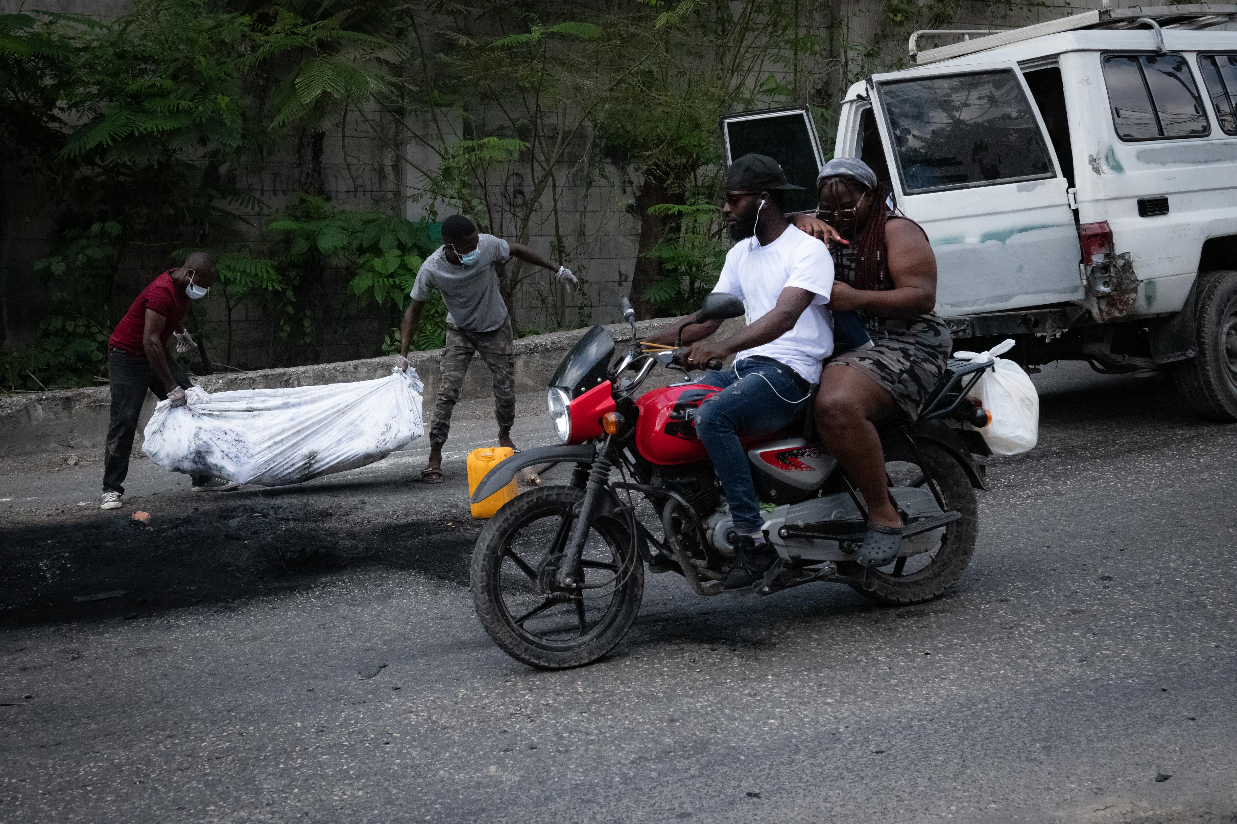 Dos hombres cargan el cuerpo de una persona en Puerto Príncipe, Haití (EFE/ Johnson Sabin/Archivo)