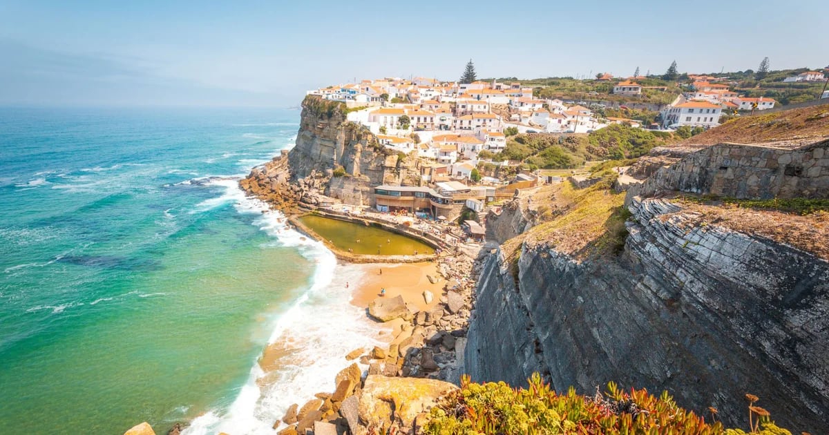 A vila em Portugal à beira de uma falésia que tem uma piscina natural na praia