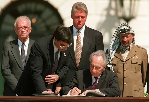 Shimon Peres firma los acuerdos de Oslo. Detrás: Isaac Rabin, Bill Clinton y Yaser Arafat (AFP)