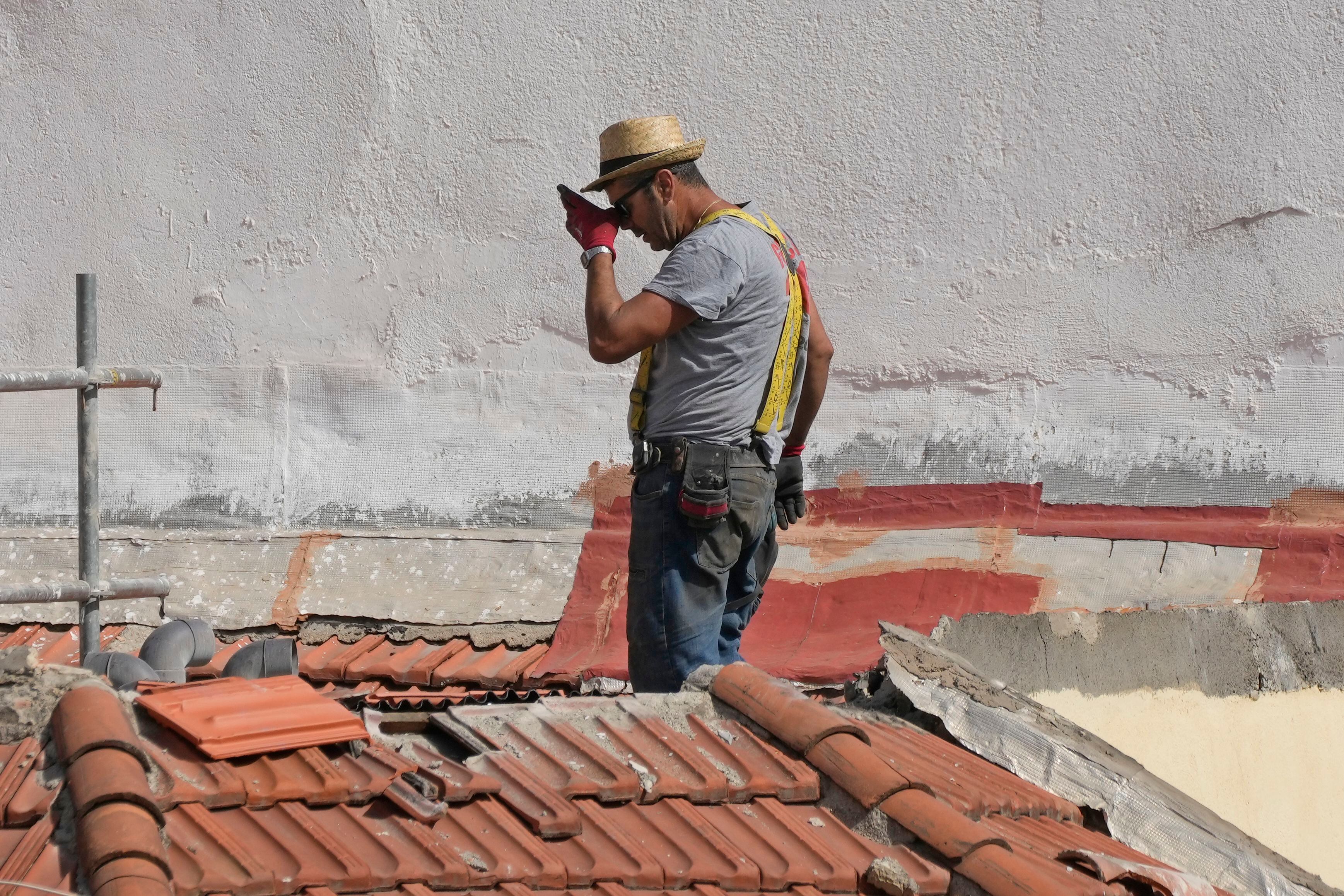 Un trabajador se seca el sudor en el techo de un edificio en Madrid, martes 8 de agosto de 2023. España sufrirá varios días de calor extremo con temperaturas superiores a 40 grados. (AP Foto/Paul White)