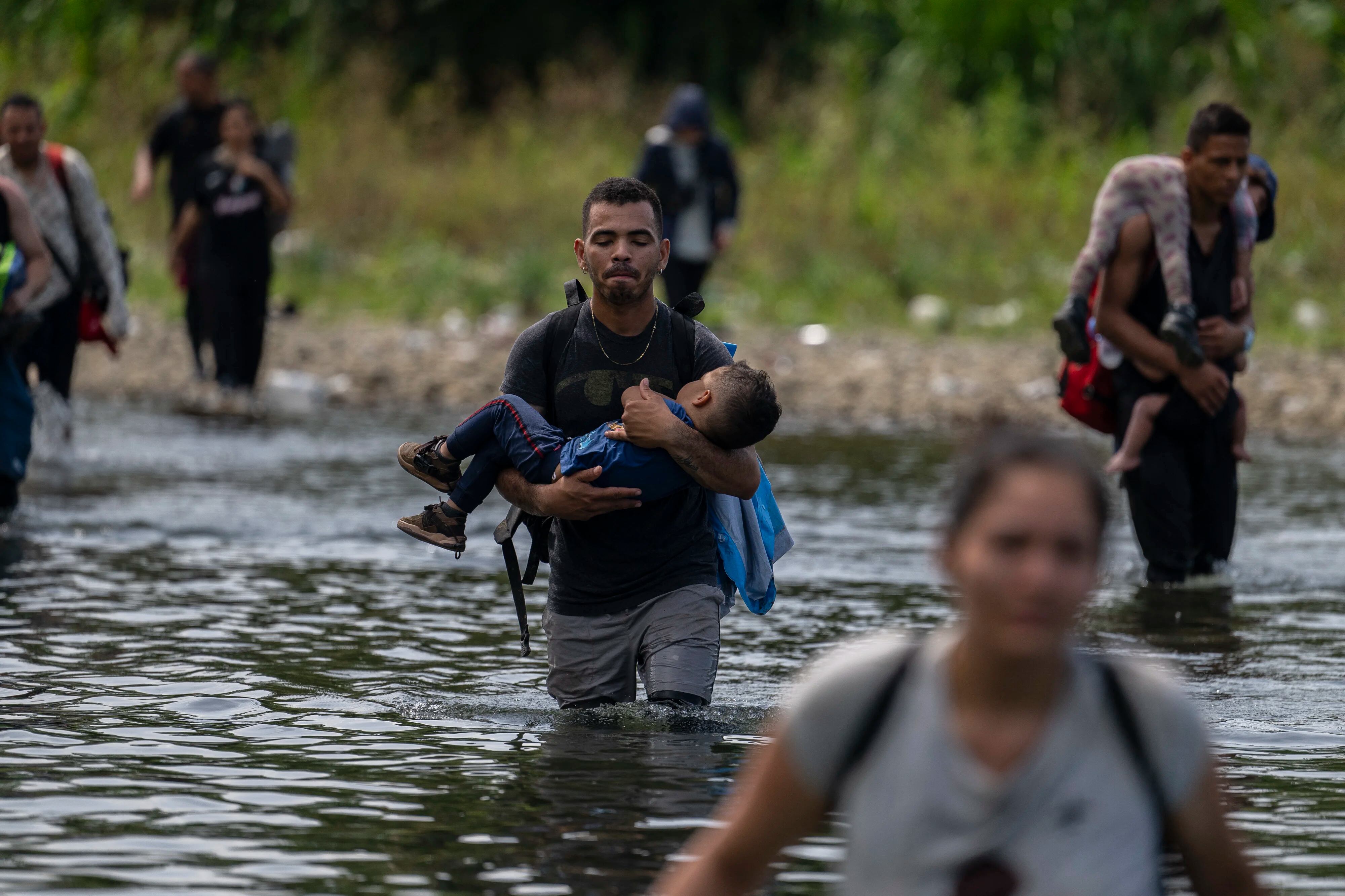 Migrants cross the Tuquesa river near Bajo Chiquito village, the first border control of the Darien Province in Panama, on September 22, 2023. The clandestine journey through the Darien Gap usually lasts five or six days, at the mercy of all kinds of bad weather. More than 390,000 migrants have entered Panama through this jungle so far this year, far more than in all of 2022, when there were 248,000, according to official Panamanian data. (Photo by Luis ACOSTA / AFP)