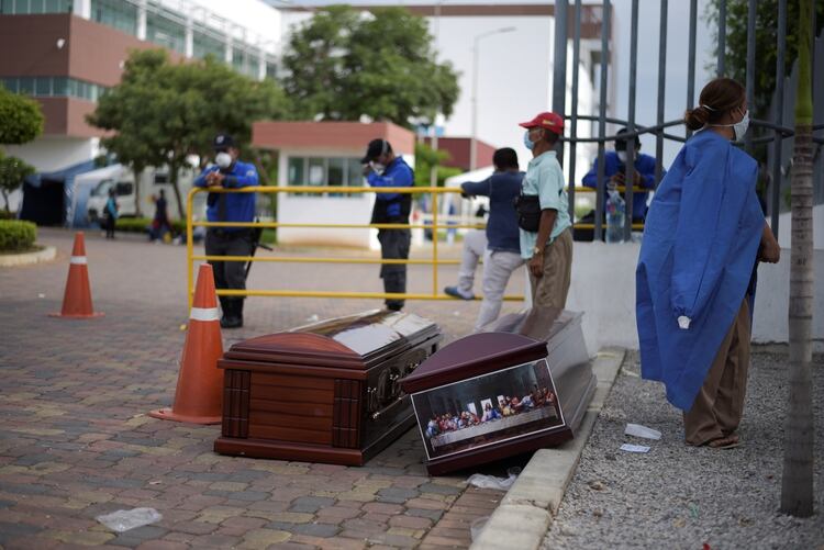 Dos personas aguardan la entrega de cuerpos con los ataúdes listos en la puerta del Hospital General de Guasmo Sur, en Guayaquil (REUTERS/Vicente Gaibor del Pino)