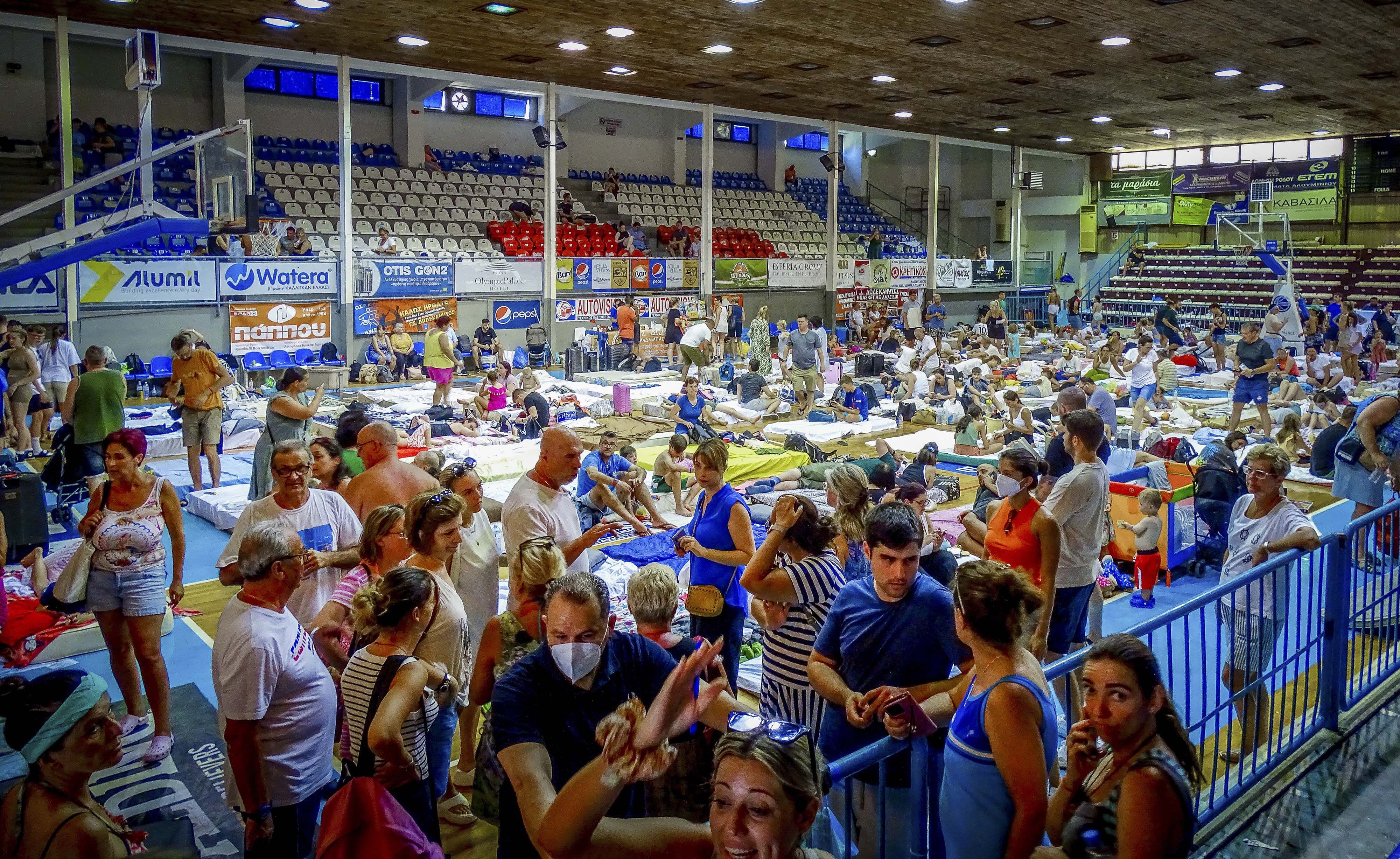 Los evacuados se sientan dentro de un estadio luego de su evacuacin durante un incendio forestal en la isla de Rodas, Grecia, el domingo 23 de julio de 2023. (Argyris Mantikos/Eurokinissi va AP)