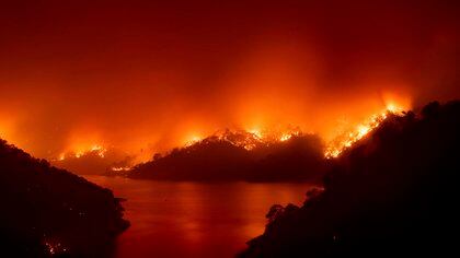 Flames from the LNU Lightning Complex fires burn around Lake Berryessa in unincorporated Napa County, Calif., on Wednesday, Aug. 19, 2020. Fire crews across the region scrambled to contain dozens of wildfires sparked by lightning strikes. (AP Photo/Noah Berger)