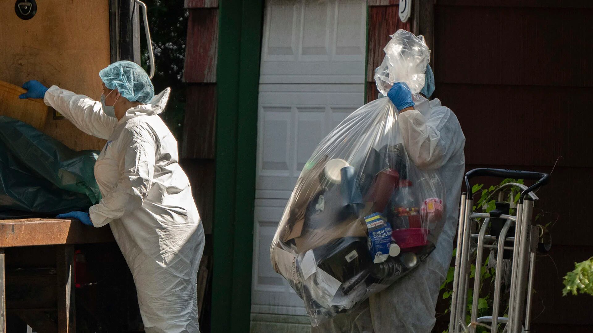 Un agente del laboratorio criminalístico mueve una bolsa de plástico con objetos mientras las fuerzas del orden registran la casa de Rex Heuermann (AP)