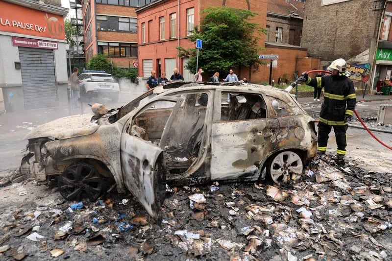 Los bomberos extinguen el fuego de un coche, quemado durante los enfrentamientos nocturnos entre manifestantes y la policía (REUTERS/Pascal Rossignol)