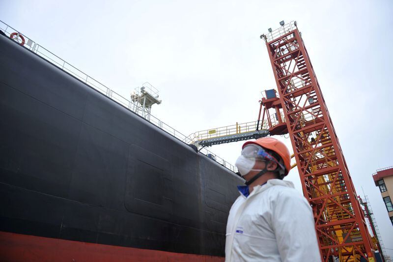 FOTO DE ARCHIVO. Un trabajador lleva una mascarilla protectora mientras observa un carguero en el puerto de Qingdao, China. Marzo 26, 2020. China Daily via REUTERS