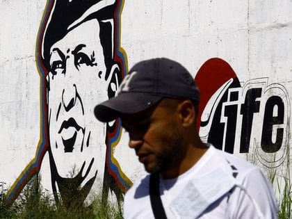Un venezolano delante de una reproducción de Hugo Chávez