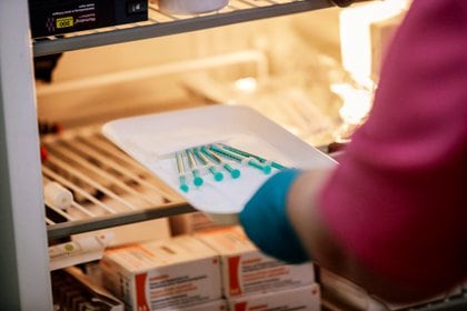 A healthcare worker takes syringes with Pfizer-BioNTech coronavirus disease (COVID-19) vaccine  out of a fridge in a doctors' practice in Berlin, Germany, April 7, 2021. REUTERS/Hannibal Hanschke