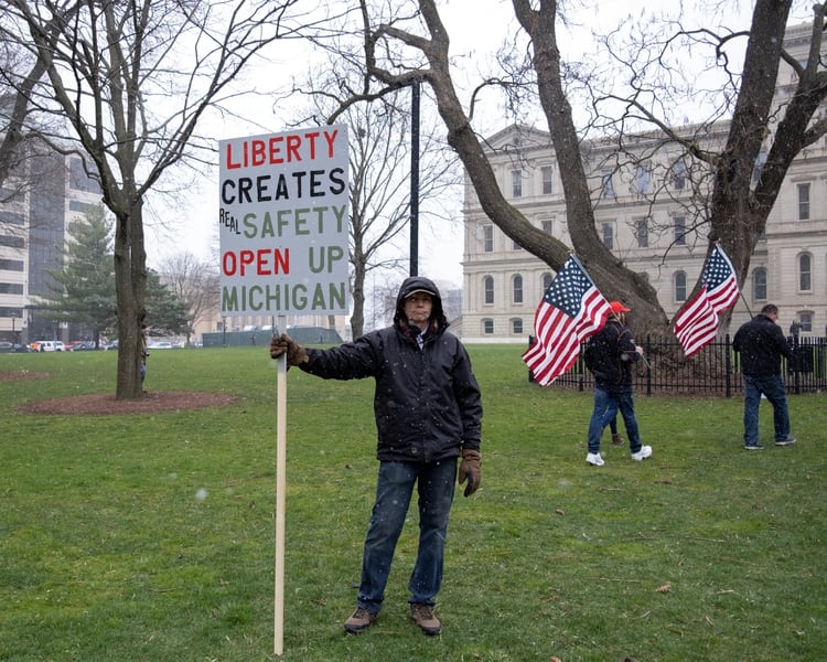 Un hombre sostiene una pancarta contra el bloqueo en Michigan (Reuters/ Seth Herald)