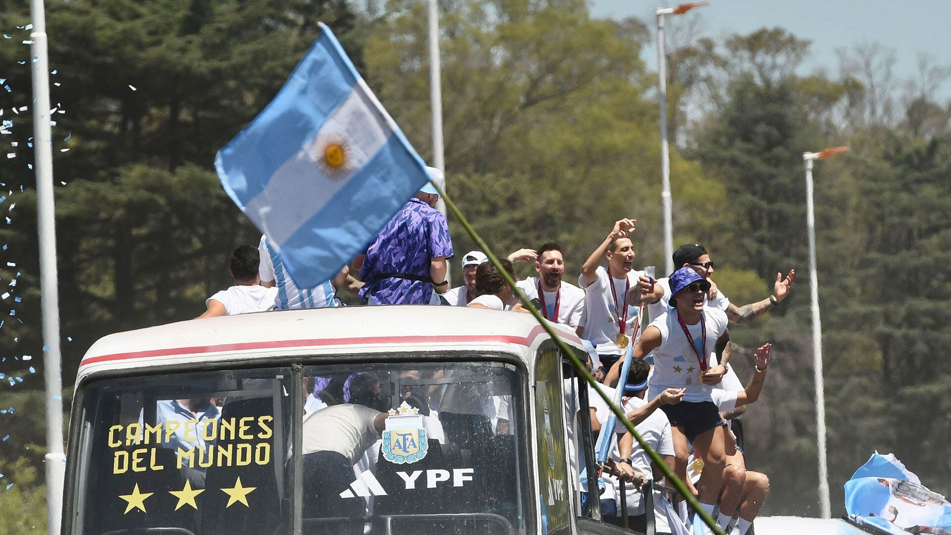 La selección argentina saluda a la gente que rodea la autopista con banderas albicelestes
