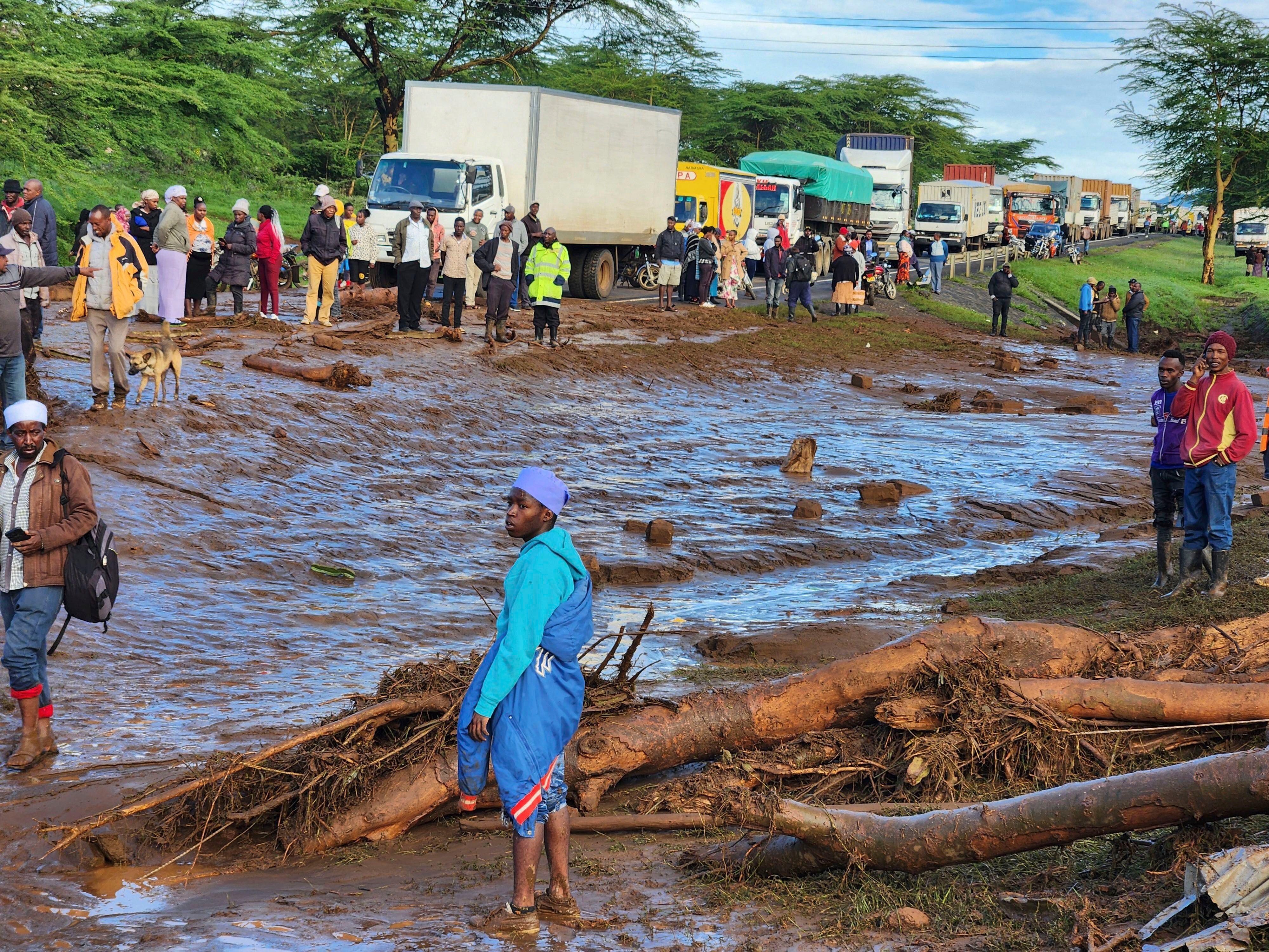 Gente reunida en la carretera principal tras la ruptura de una represa en el poblado de Kamuchiri