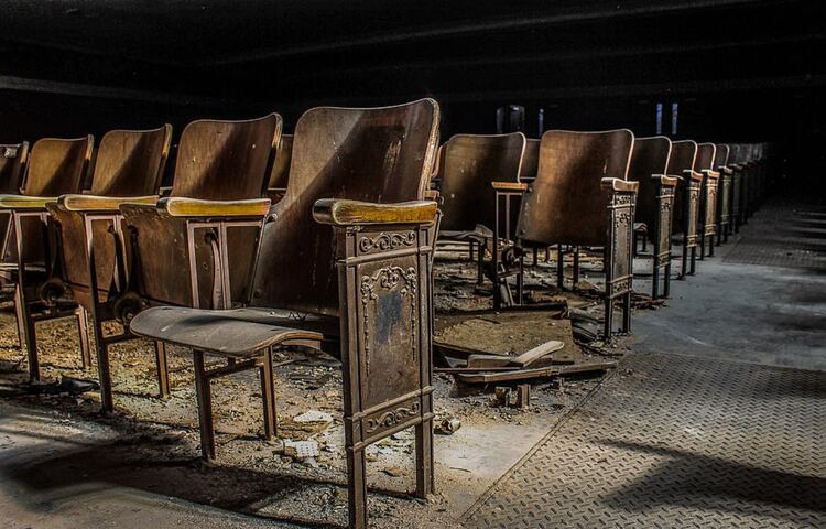 Asientos de madera descubiertos que se están cayendo a pedazos en el auditorio de una secundaria abandonada (Foto: Leland Kent)