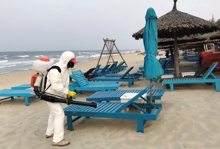 Un fumigador desinfecta las sillas de un parador en una playa de Hoi An, en Vietnam [10 de marzo de 2020] 