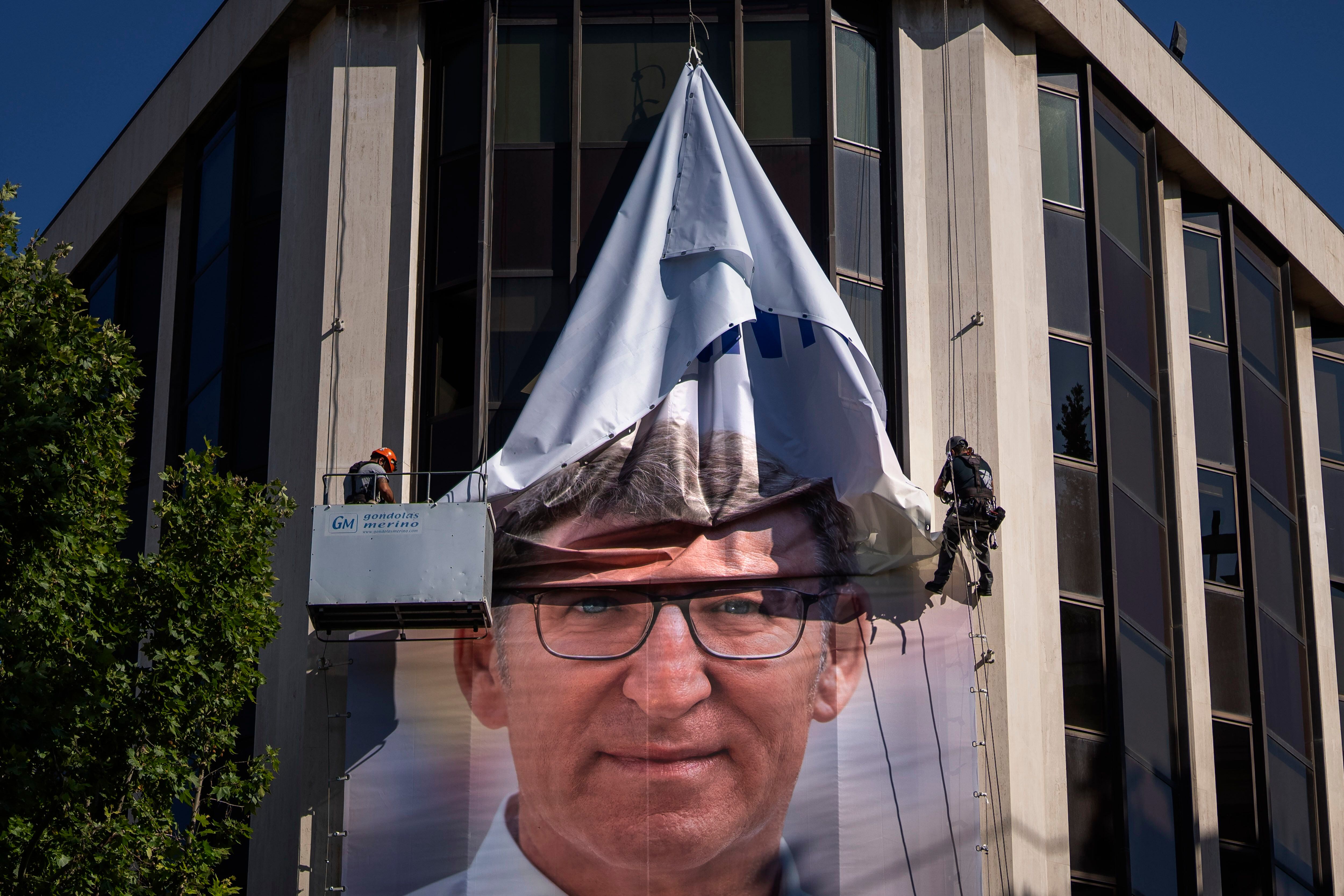 Trabajadores retiran el cartel electoral de Alberto Núñez Feijóo, presidente del PP, de la sede nacional del partido, en la calle Génova de Madrid. (AP/Emilio Morenatti)