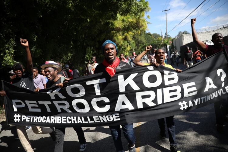 Manifestantes sostienen una bandera con la leyenda “¿Dónde está el dinero de Petrocaribe?” (REUTERS/Andres Martinez Casares)
