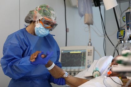 A hospital staff member treats a patient suffering from the coronavirus disease (COVID-19), in the Intensive Care Unit (ICU) at the Hospital Clinic, after Catalonia's government imposed new restrictions in an effort to control a COVID-19 third wave, in Barcelona Spain February 3, 2021. Picture taken February 3, 2021. REUTERS/Nacho Doce