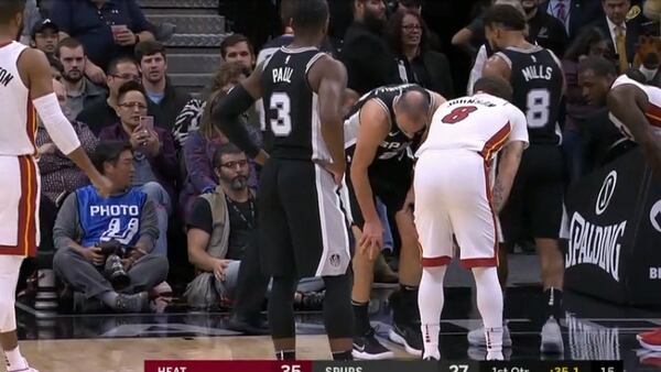Los jugadores de Miami Heat y San Antonio Spurs alrededor de Manu Ginóbili, para saber su estado de salud