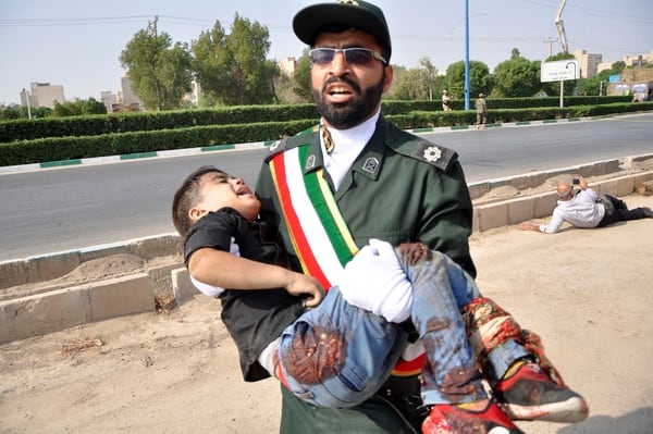 Un miembro de la Guardia Revolucionaria iraní cargando a un niño herido (AP)