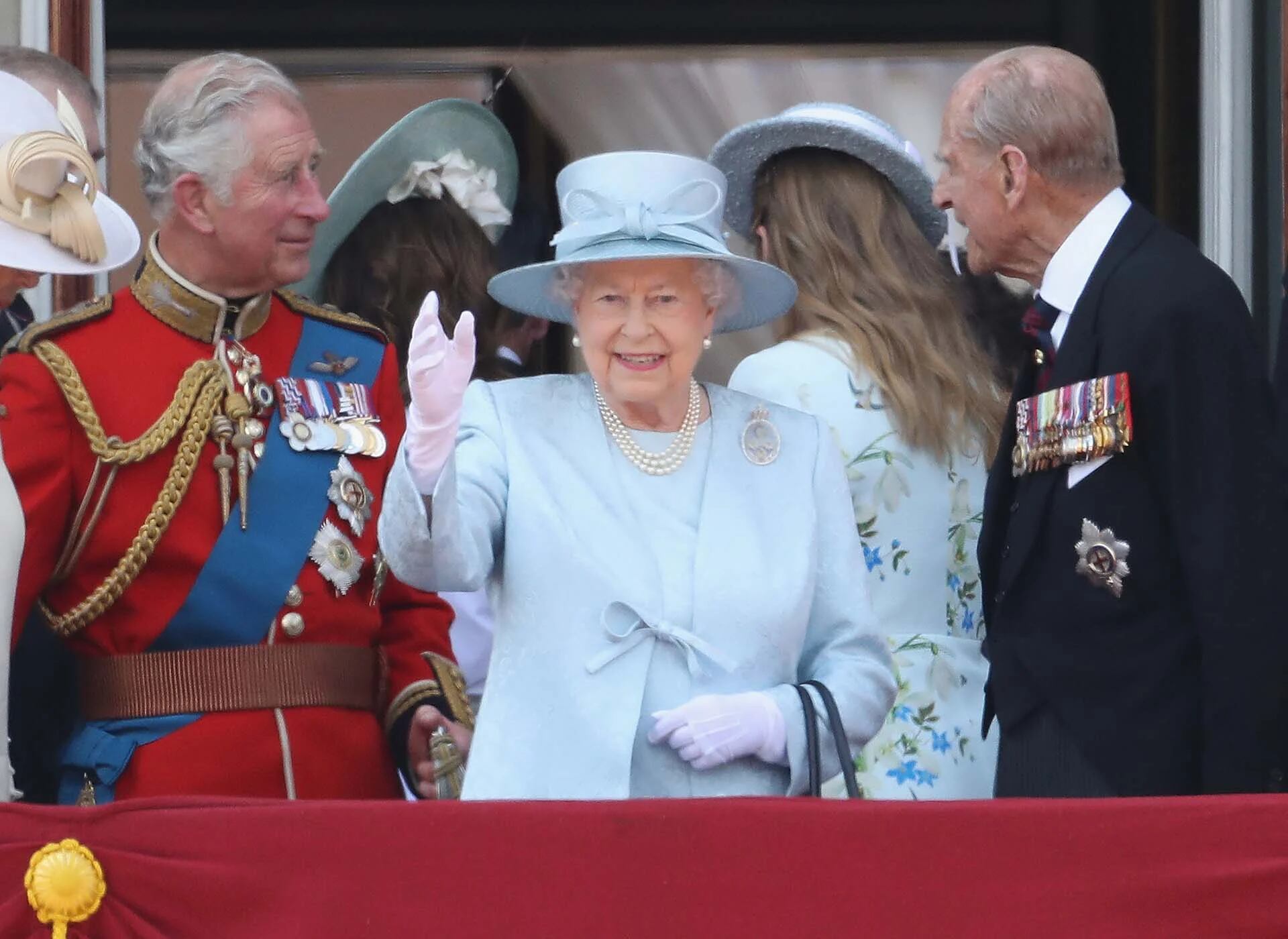 La reina saluda junto a su hijo, el príncipe Carlos, y su marido, Felipe, duque de Edimburgo