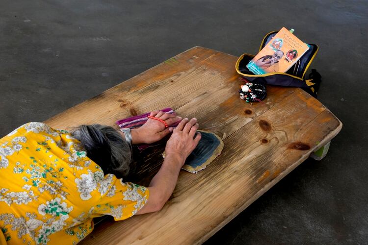 Una mujer tibetana exiliada reza frente a un retrato del dalái lama, luego de su hospitalización (AP)
