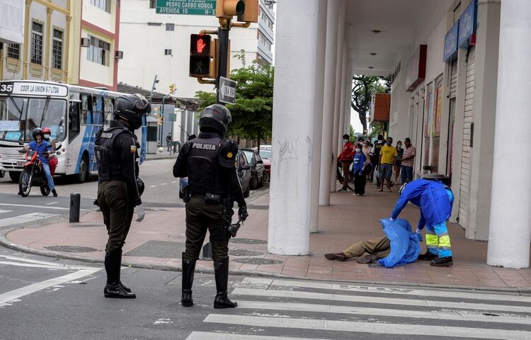 Un funcionario tapa un cuerpo ante la presencia de policías (REUTERS/Vicente Gaibor del Pino)