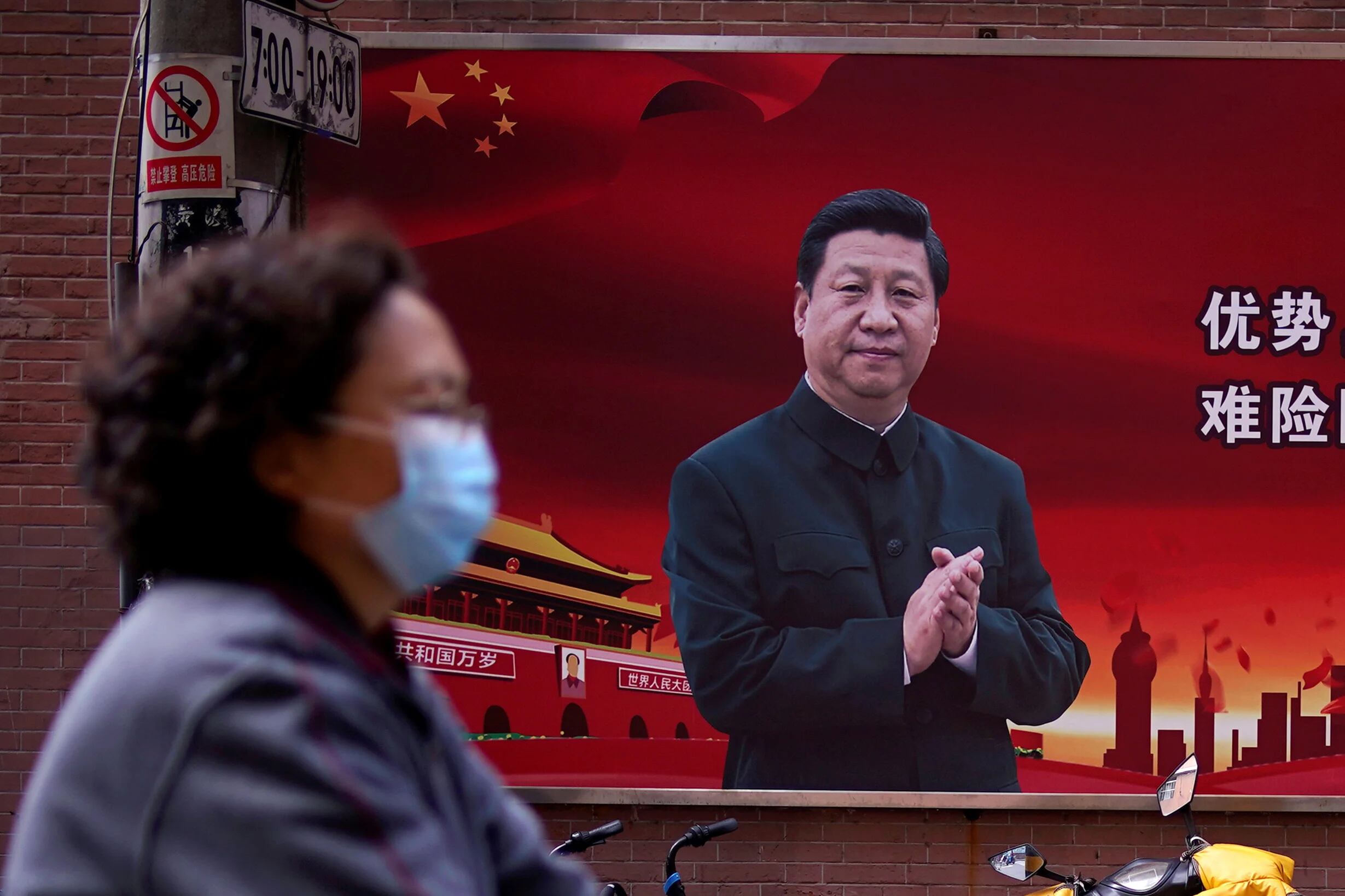 FOTO DE ARCHIVO: Una mujer con una máscara protectora se ve más allá de un retrato del presidente chino Xi Jinping en una calle en Shanghai, China (Reuters)