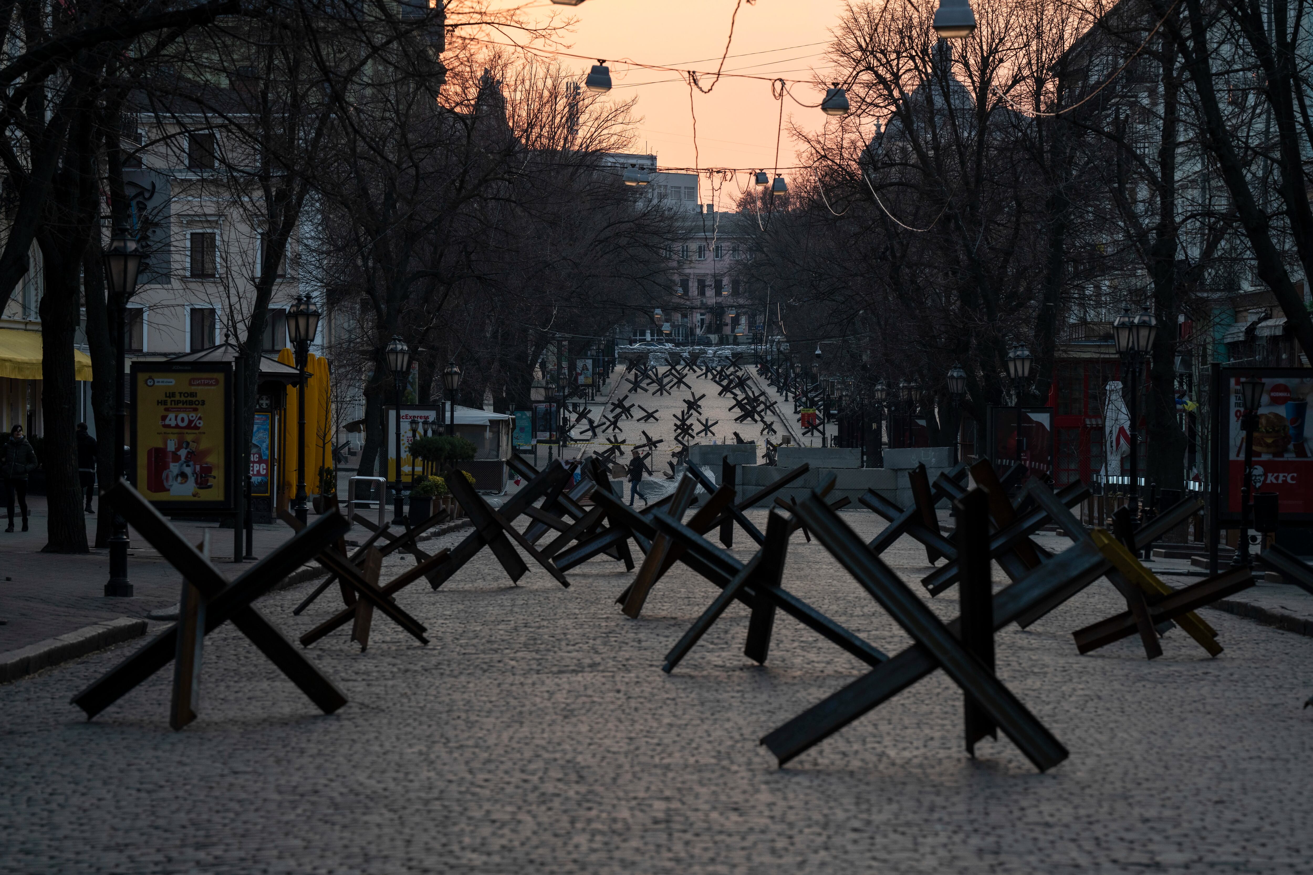 Una mujer camina a través de barricadas antitanque colocadas en una calle como preparación para una posible ofensiva rusa, en Odesa, el jueves 24 de marzo de 2022.