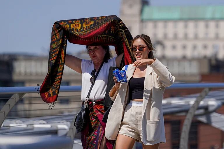 La gente se cubre del sol en el Puente del Milenio durante una ola de calor, en Londres  