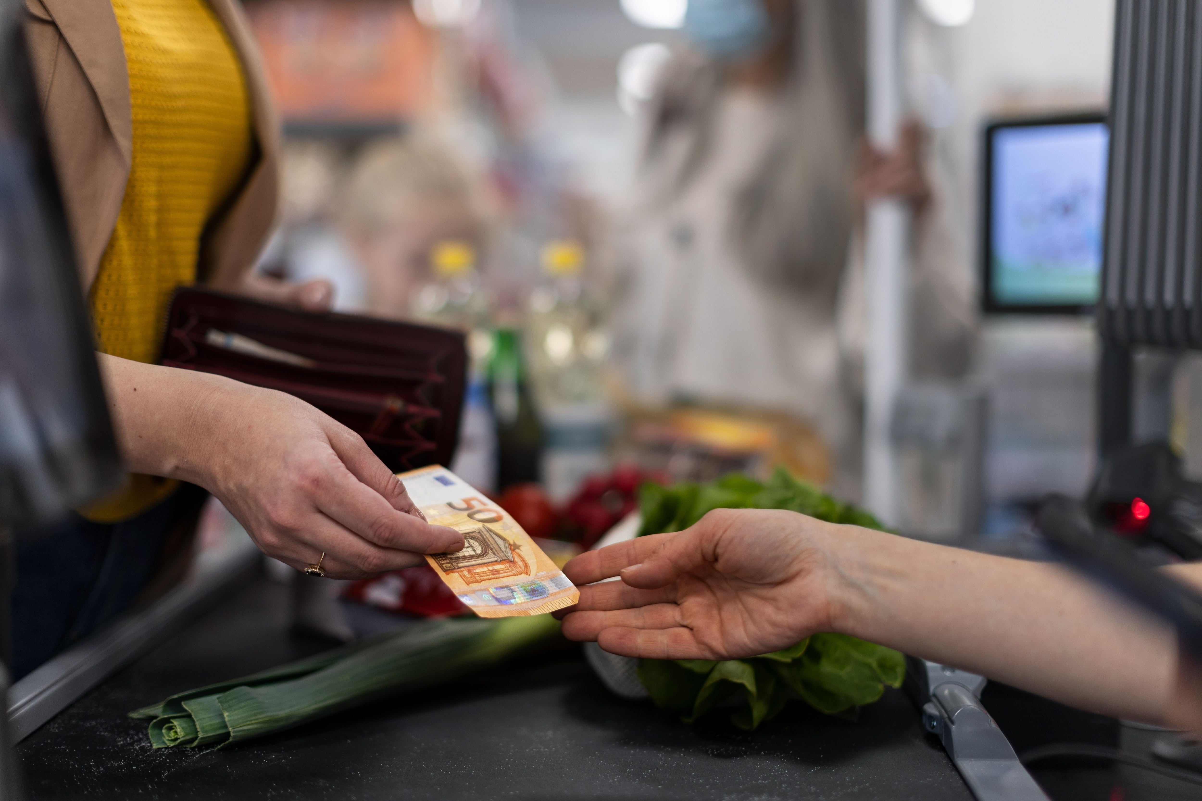 Una mujer paga con dinero en efectivo en el supermercado. (Shutterstock)