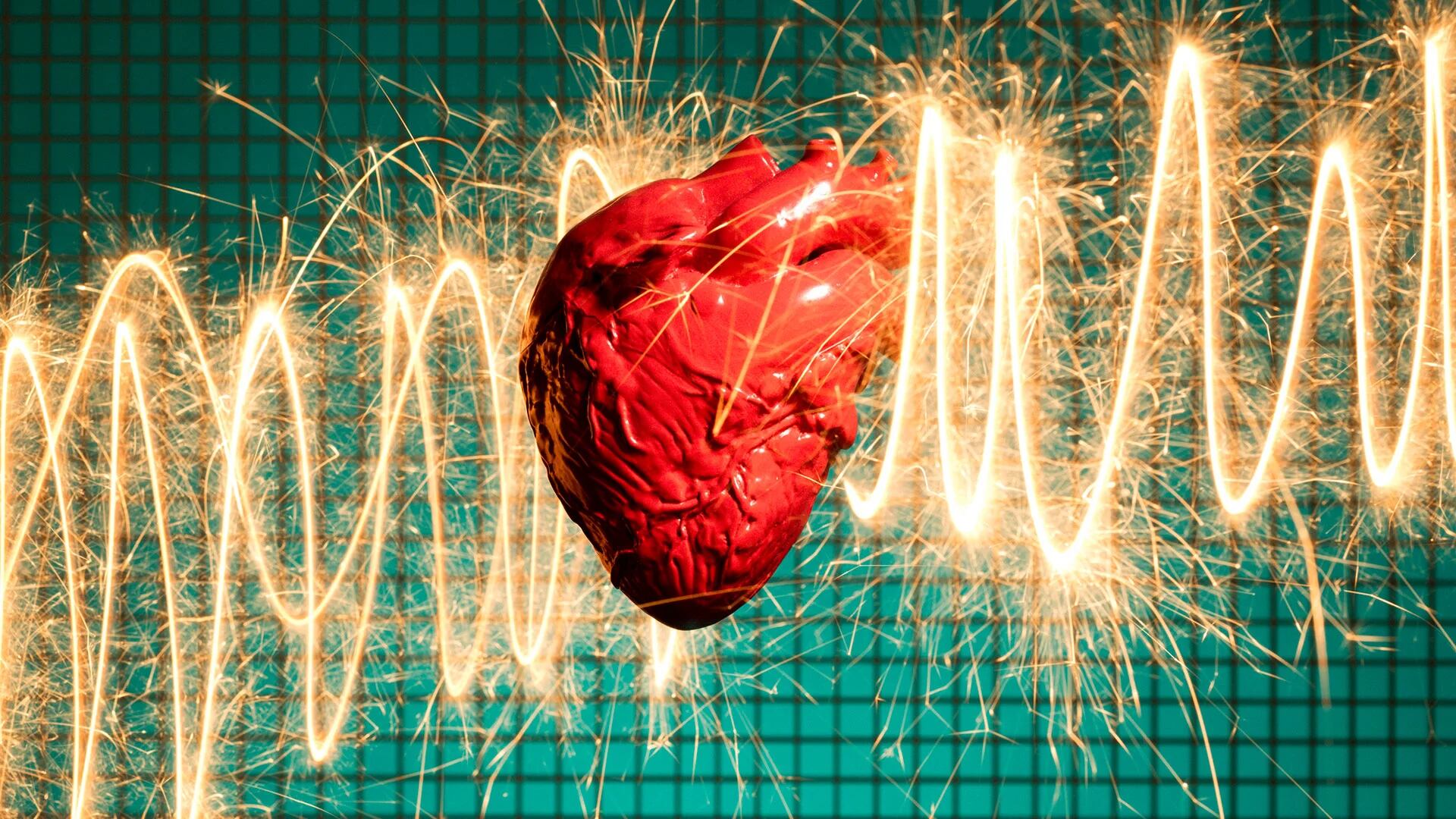 Model of human heart in front of wave pattern of sparks on green grid patterned background (Getty)