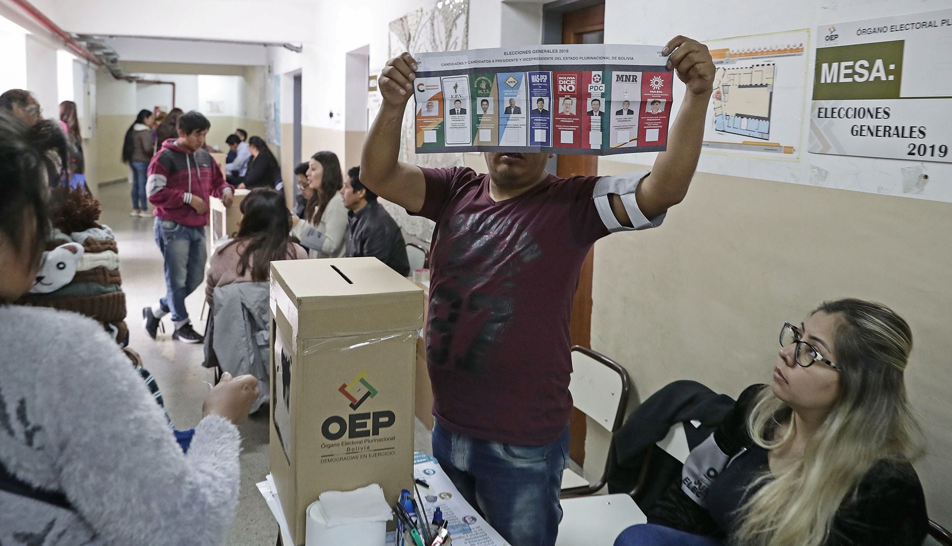 Una de las autoridades de mesa muestra la boleta a los ciudadanos bolivianos residentes en Buenos Aires que se preparar para emitir su voto