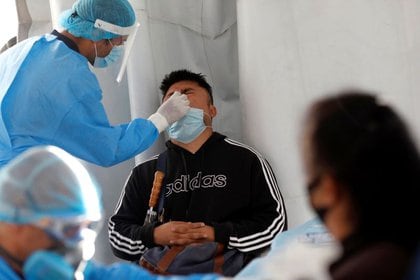 Un trabajador de salud con equipo de protección personal toma una muestra de un hombre para un prueba del COVID-19 afuera del estadio Azteca, en Ciudad de México, México. 25 de noviembre de 2020. REUTERS/Henry Romero
