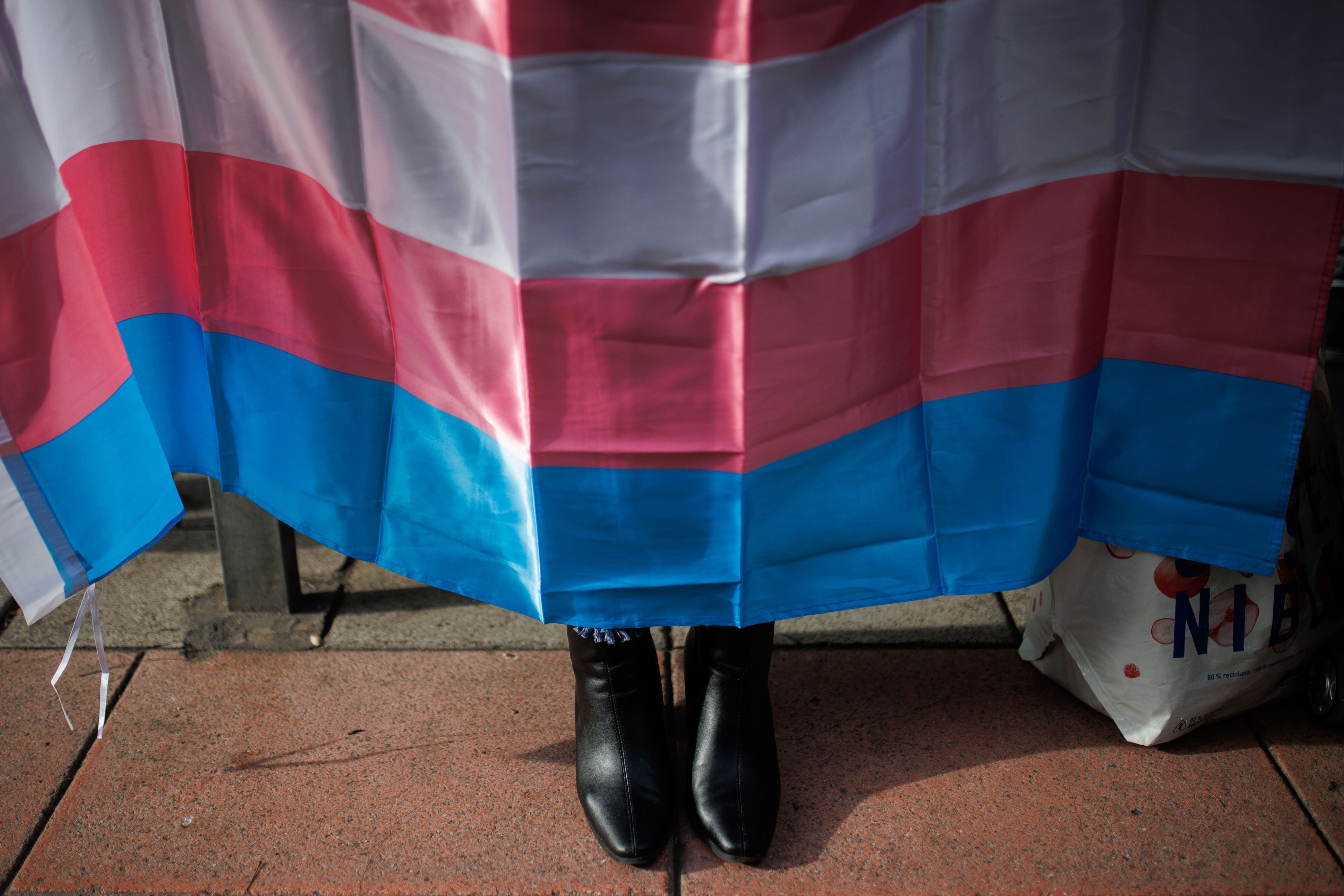 Los zapatos de una mujer por debajo de una bandera trans. (Alejandro Martínez Vélez/Europa Press)