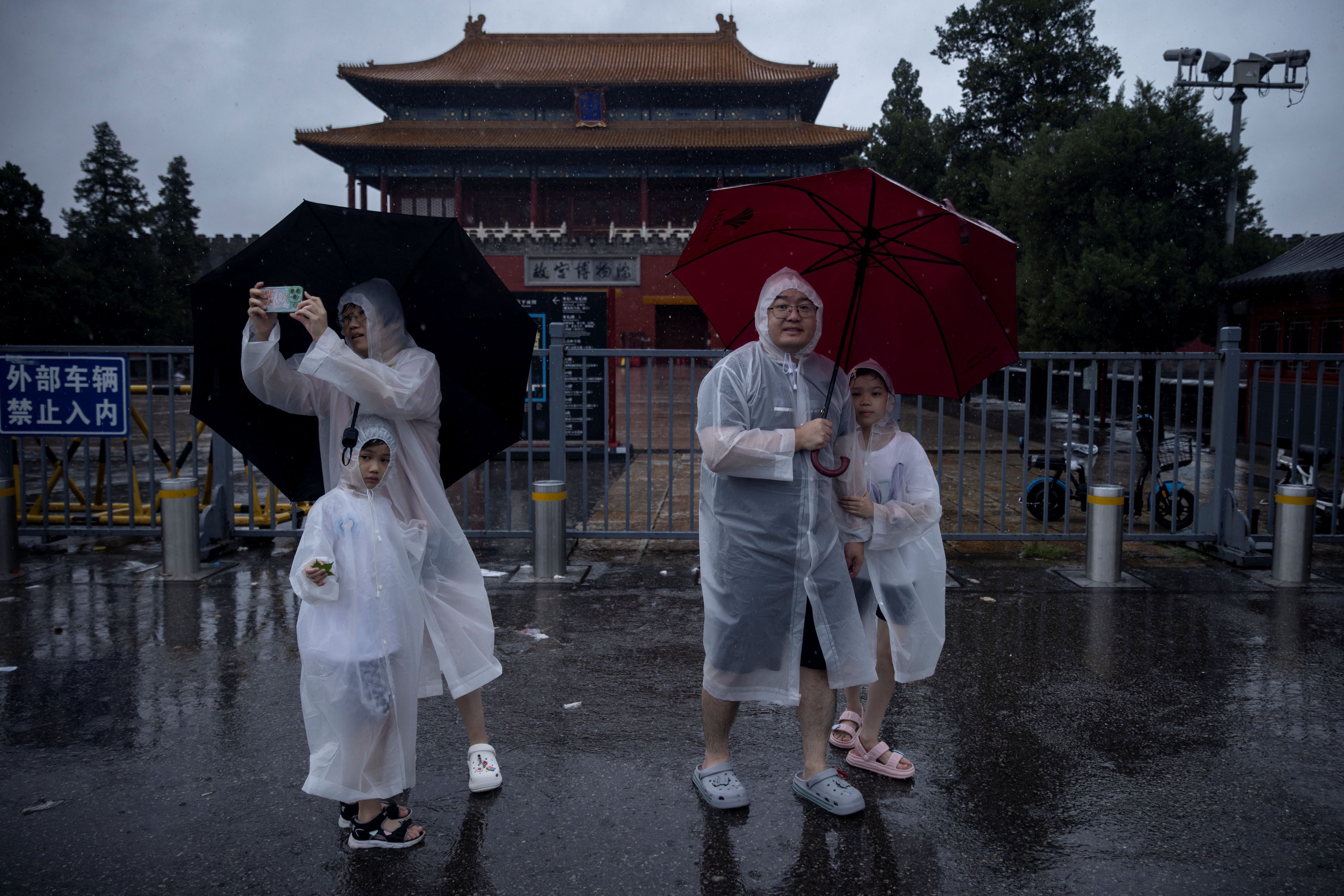 Personas con impermeables se paran en las puertas cerradas de la Ciudad Prohibida durante las fuertes lluvias en Beijing, China, el 30 de julio de 2023. REUTERS/Thomas Peter