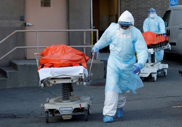 Trabajadores del área de salud transportan los cuerpos de fallecidos a causa del coronavirus en Brooklyn, Ciudad de Nueva York. Estados Unidos (REUTERS/Andrew Kelly)