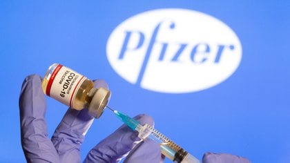 FILE PHOTO: FILE PHOTO: A woman holds a small bottle labeled with a "Coronavirus COVID-19 Vaccine" sticker and a medical syringe in front of displayed Pfizer logo in this illustration taken, October 30, 2020. REUTERS/Dado Ruvic/File Photo/File Photo