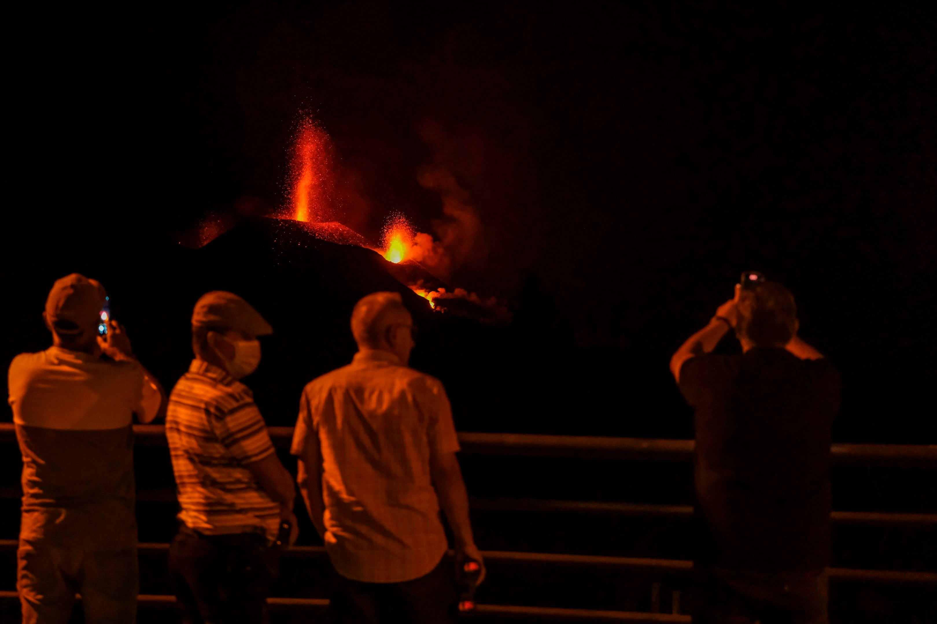 Varios vecinos evacuados contemplan el volcán. EFE/Ángel Medina G.